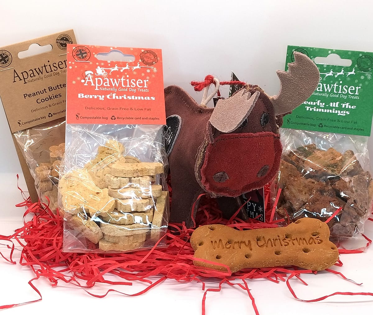 A reindeer soft toy shown alongside 3 bags of dog treats and a Merry Christmas bone.